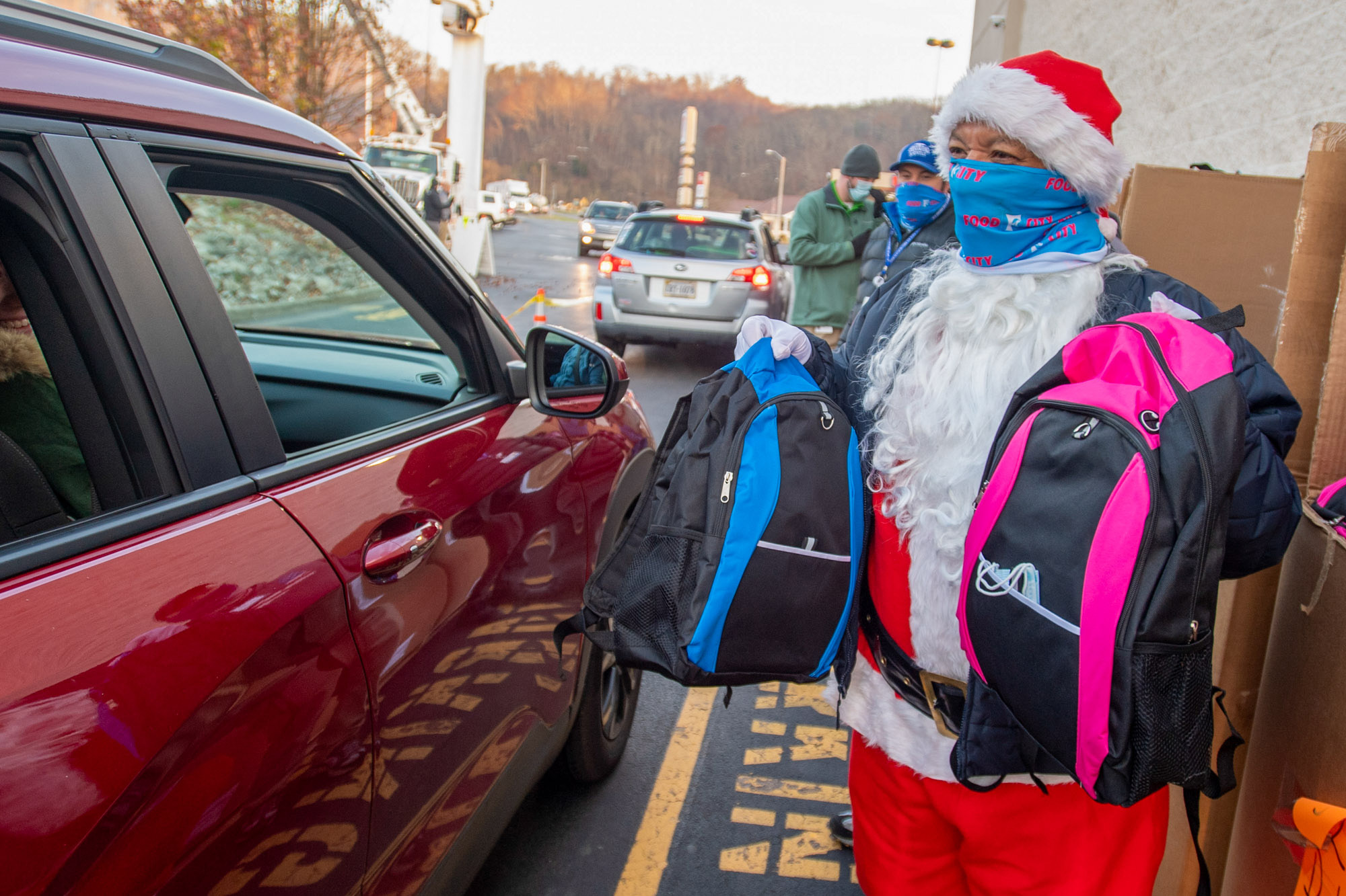 Santa handing gifts to people in cars